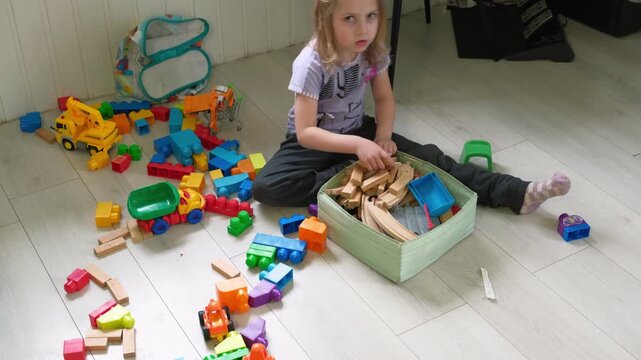 Child puts the toys in the box to establish order. Kid 5 years old establish order. Caucasian little girl tidying. The toddler baby himself cleans up, collects toys in the nursery after game playing.