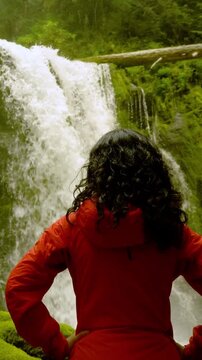 Woman enjoying the view of an amazing waterfall and moss covered rocks in Oregon. Vertical video.