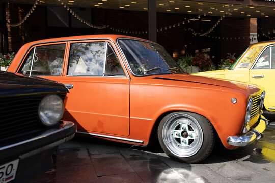 Classic soviet vintage cars lada vaz 2101 on city street exhibition near cafe under blue sky