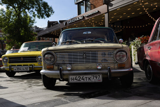 Classic soviet vintage cars lada vaz 2101 on city street exhibition near cafe under blue sky