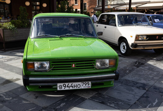 Classic bright green soviet sedan car lada vaz 2105 at city street exhibition near restaurant