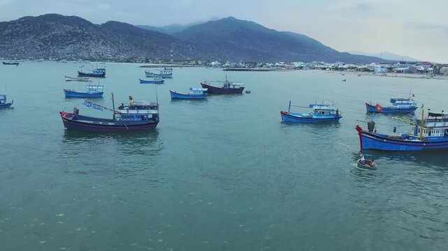 Ca Na Bay in Ninh Thuan, Vietnam viewed from above at noon in summer with hundreds of fishing boats moored and fishing villages below.