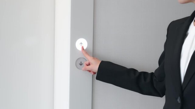 エレベーターの上昇ボタンを押す女性