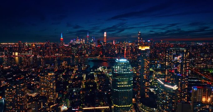 Bright neon lights illuminating the tops of the highest buildings of New York City, USA. Night scenery of metropolis from drone.