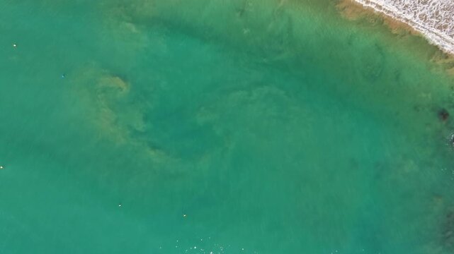 Aerial view of a tropical beach with waves and rocks beside rainforest