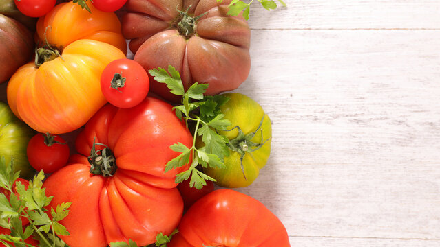 variety of fresh heirloom tomatoes on white wooden background with copy space