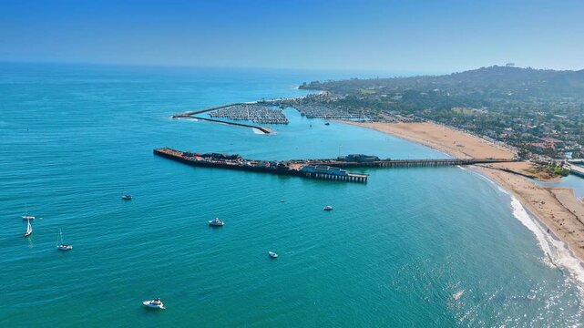 Footage over the boats and yachts on the beautiful blue waterscape. Approaching Stearns Wharf in Santa Barbara County, California.