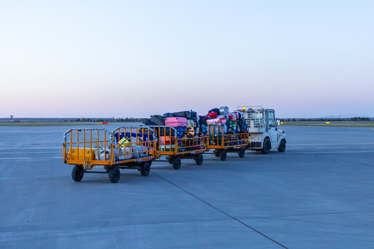 Tow tractor pulling luggage carts at evening airport