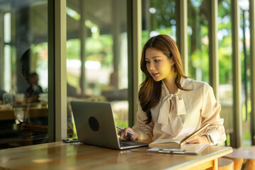 Fototapeta premium Asian woman remote working on laptop in cafe