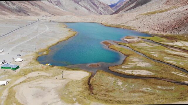 Drone tilts up from blue Chagar Tso lake to majestic Ladakh mountains
