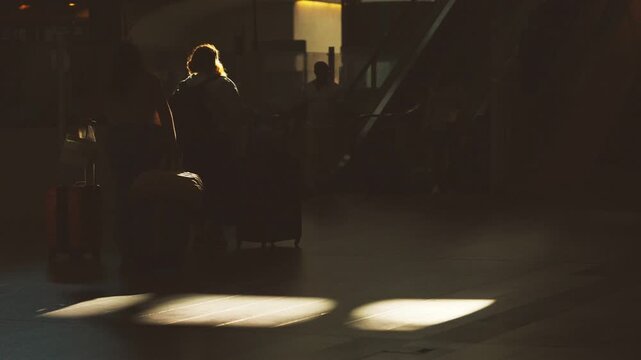 Silhouetted figures with luggage walking through a brightly lit airport terminal, sunlight streaming across the floor, creating dynamic shadows and reflections