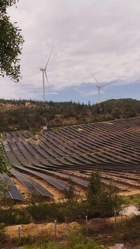 Solar panels in the foreground and wind turbines in the background near Quy Nhon, Vietnam. Renewable energy infrastructure supporting sustainable electricity generation, green technology and clean