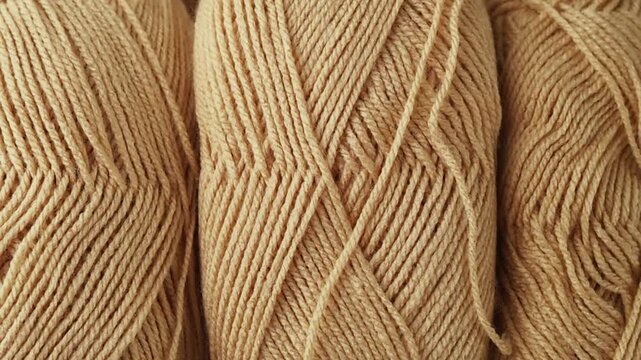 Extreme close-up panning shot across tightly wound beige yarn skeins. Detailed texture of natural wool threads, perfect for crafting backgrounds, textile design, and cozy lifestyle concepts.