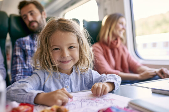 Child drawing with parents during a train journey, representing family rail travel, vacation with children and calm onboard activities