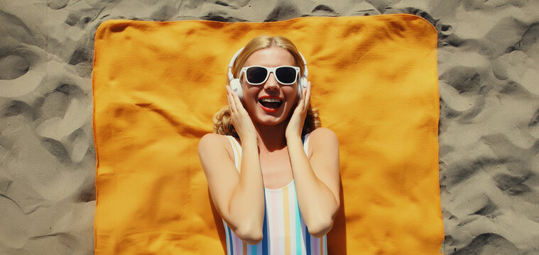 Summer vacation, happy cheerful woman listening to music lying on the beach, relaxed girl on towel