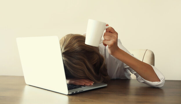 Tired overworked sleepy woman employee working with laptop sitting at desk in office
