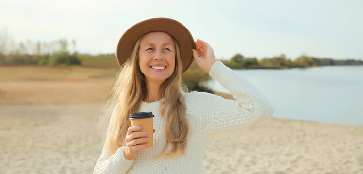 Stylish happy woman standing on beach, girl smiles, looking away on sea