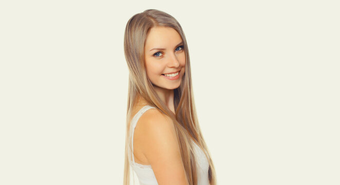 Portrait of beautiful blonde smiling young woman with long hair on white background