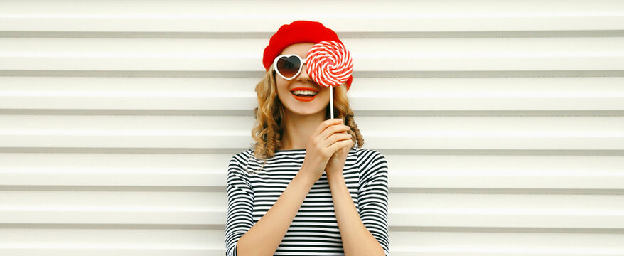 Portrait of happy cheerful smiling young woman holding colorful lollipop on white background