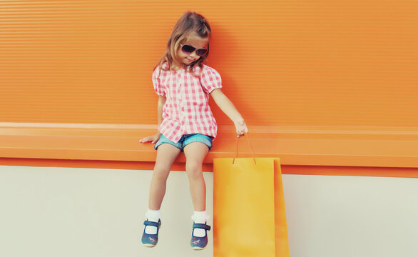 Little girl child with shopping bags posing on city street