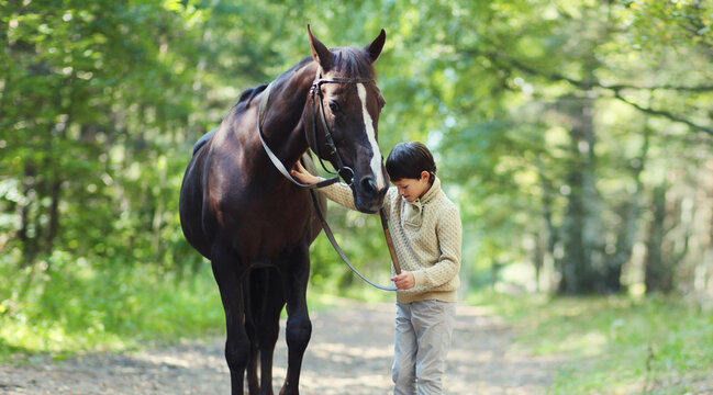 Teenager boy kid with horse walking in summer forest, horseback riding