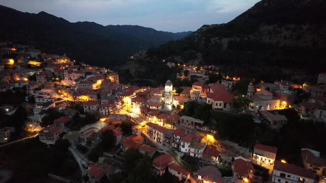 Aerial establishing shot of mountain village lights and church tower