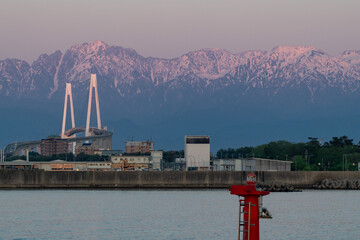 新湊大橋と夕日に染まる剱岳と立山 © easterlily.photos