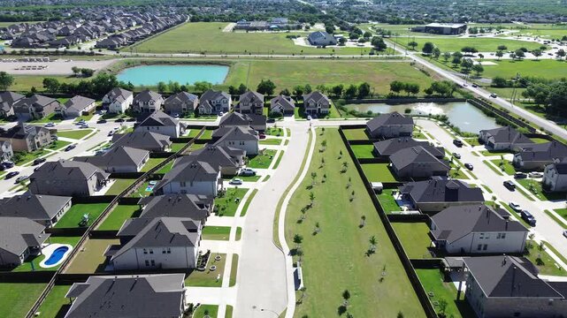 Greenbelt residential divide in Arlington, TX highlights two parallel rows of homes separated by landscaped corridor with young trees open lawn. Visible ponds distant rooftops in upscale area