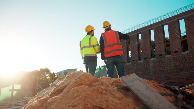 Men, team and discussion on construction site for planning, building development and space. Low angle, engineers and outdoor with meeting for inspection requirements, renovation progress and back