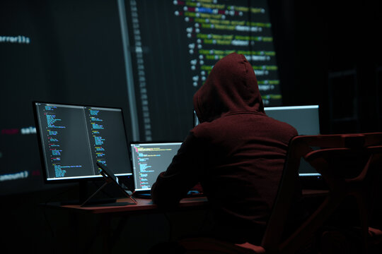 Programmer Hacker Working at Multiple Computer Monitors