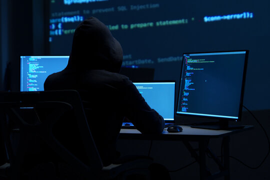 Programmer Hacker Working at Multiple Monitors in Dark Room