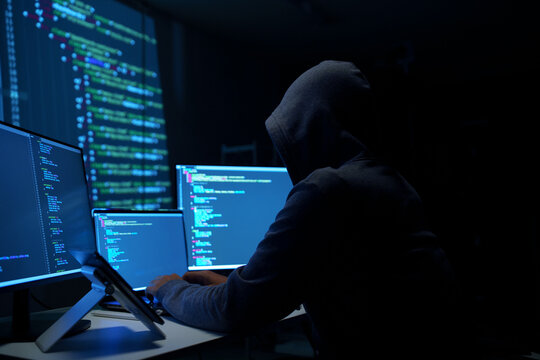 Hacker in Hoodie Working on Multiple Monitors at Night