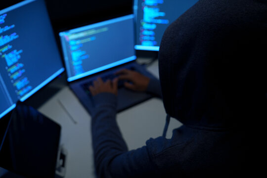 Hacker Working at Multiple Monitors in Dark Room