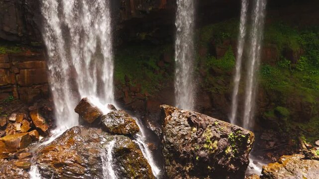 Close aerial footage of the cascading water and rocky ledges at Tad Tayicseua Waterfall, Attapeu Province, southern Laos. The drone captures the force and drama of the falls as white water crashes ove
