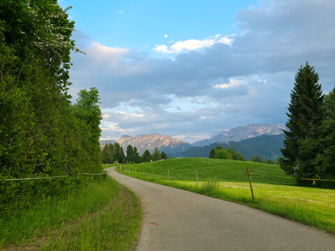 germany, radiant alpine evening above green meadows and scenic trail with glowing mountain backdrop