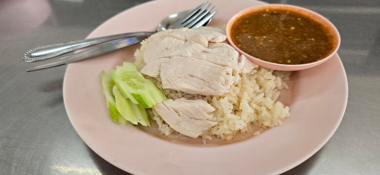  Hainanese chicken rice, Khao Man Gai With chicken topped with fermented soya beans sauce and ginger. Rice cooked in chicken broth and served with spoon-fork and boiled chicken, sliced ​​cucumber. 
