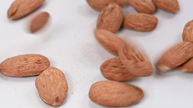 almonds falling on white surface, slow motion