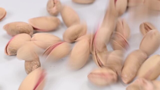 pistachios falling on white surface, slow motion
