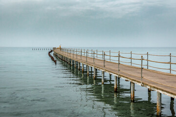 Naklejka premium Wooden pier in the sea in dusk. Beautiful seascape