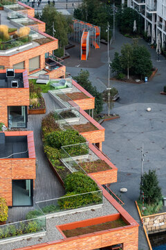 Urban garden terraces step along brick apartments above courtyard paths, with plants, balconies and residential architecture defining outdoor space