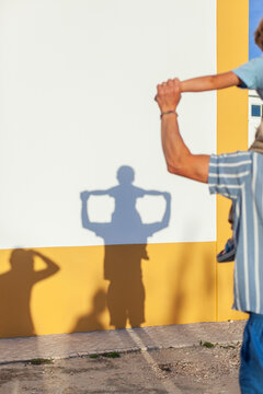 Vater und Kind machen Schattenspiel an Hauswand.