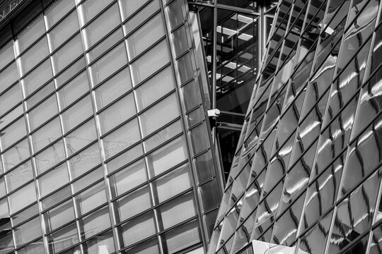 Facade grids overlap in a black and white photograph, where glass architecture, reflections and diagonal structure sharpen urban density into depth