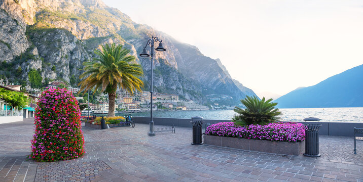 empty promenade Limone sul garda, early morning. flower pots and palm trees