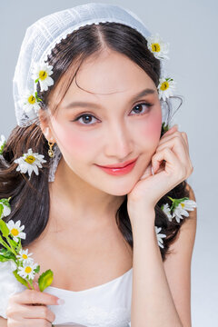 Extreme close up of Asian woman face framing with daisy flowers for botanical cosmetics skincare marketing campaign organic treatment concept holistic beauty wellness softness editorial