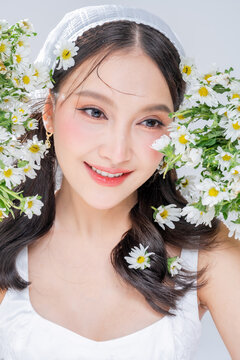 Extreme close up of Asian woman face framing with daisy flowers for botanical cosmetics skincare marketing campaign organic treatment concept holistic beauty wellness softness editorial