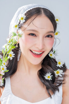 Extreme close up of Asian woman face framing with daisy flowers for botanical cosmetics skincare marketing campaign organic treatment concept holistic beauty wellness softness editorial