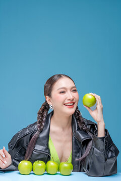 Confident Asian woman behind row of green apples for botanical cosmetics skincare marketing campaign neon street fashion aesthetic healthy lifestyle premium organic nutrition portrait stock