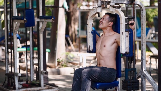 Man training chest muscles at outdoor gym with intense effort and determination
