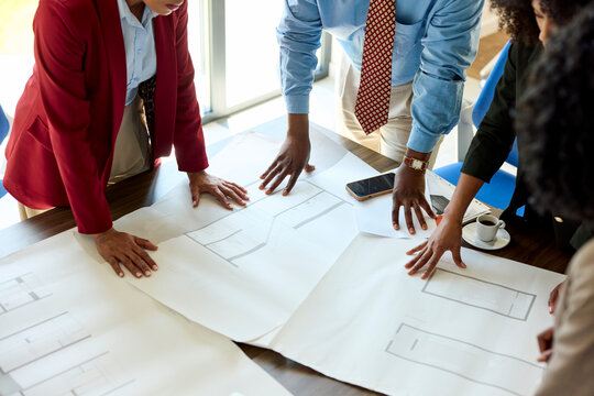 Working group examine blueprints on a desk