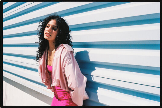 Woman with curly hair posing under sunlight